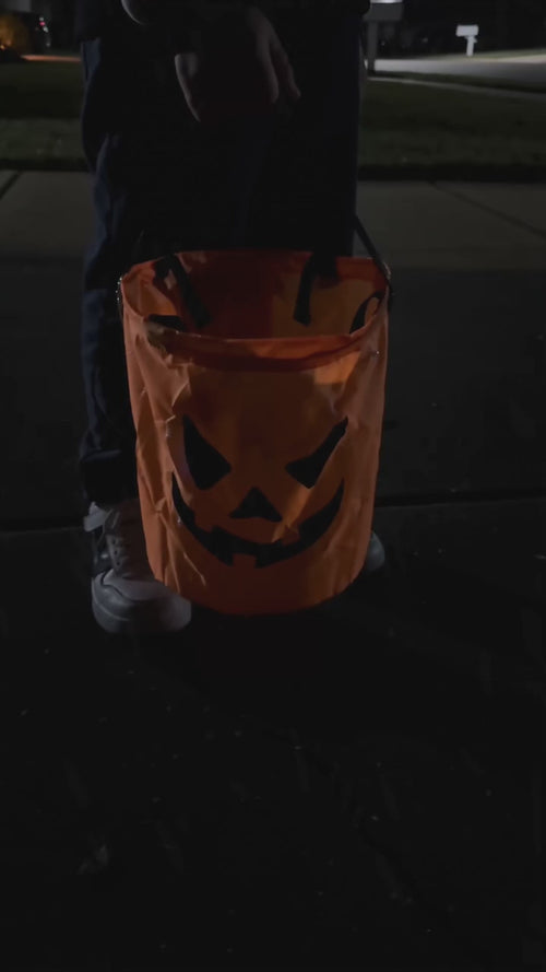 One click and the Glow Pumpkin Bucket lights up on a dark sidewalk